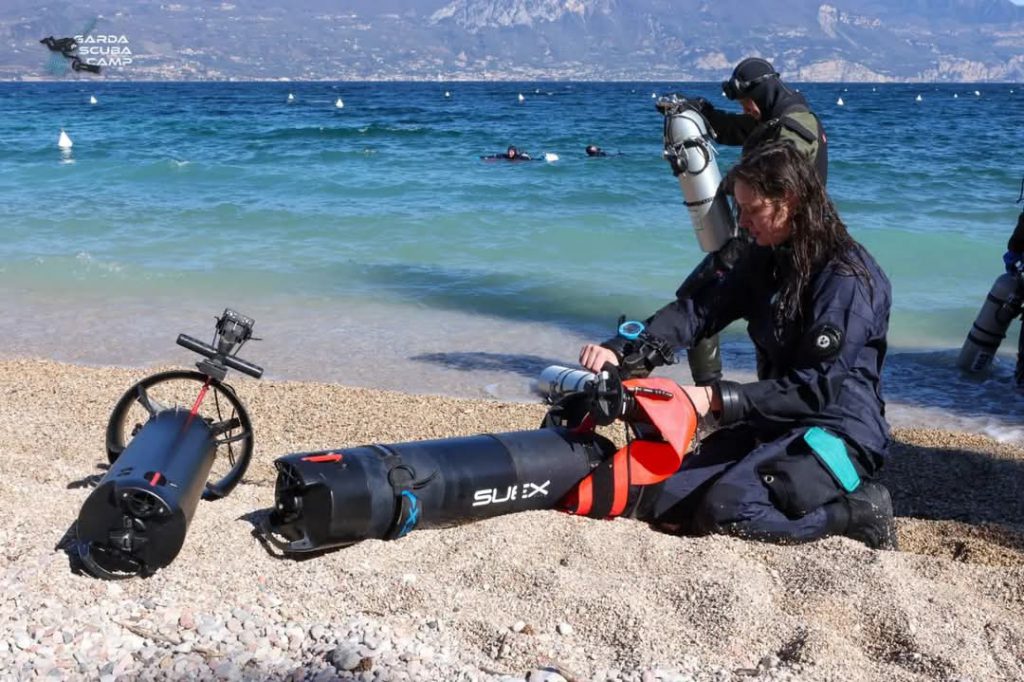 Ragazza prepara uno scooter subacqueo SUEX sulla spiaggia al Garda Scuba Camp 2025.